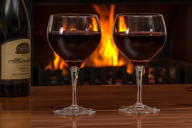 skleničky vína s hořícím krbem